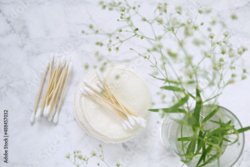 Organic wooden cotton buds,reusable tissue cosmetic sponges and gypsophila flowers on gray marble background.reasonable consumption.Zero waste.