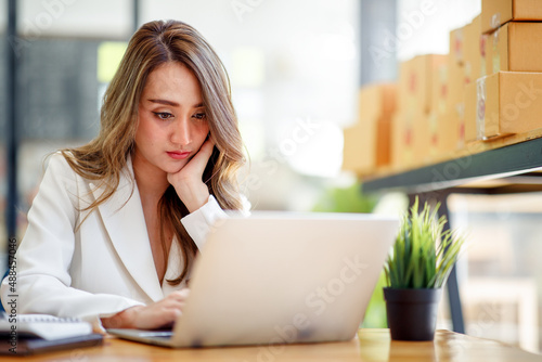 Startup SME small business entrepreneur SME or freelance Asian woman using a laptop with box, Young success Asian woman with her hand lift up, online marketing packaging box and delivery, SME concept.