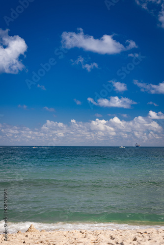 Shipping boat on a horizon next to Fort Lauderdale Beach while small recreational nautical vessels are sailing a bit closer to the shore