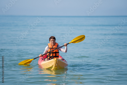 man in life jacket paddling a kayak boat in sea