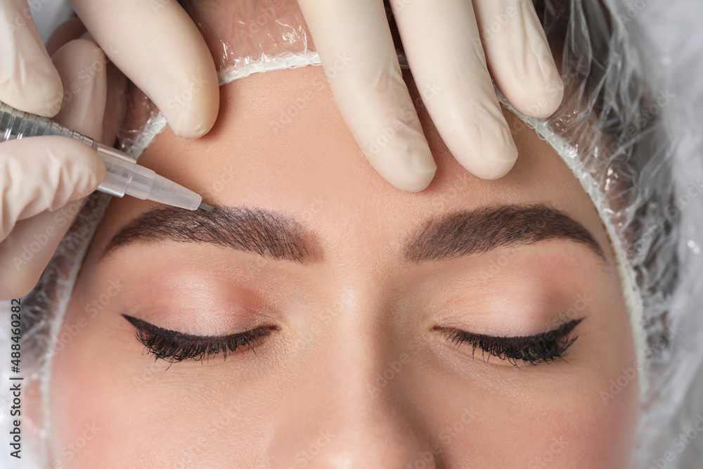 Young woman during procedure of permanent eyebrow makeup, closeup
