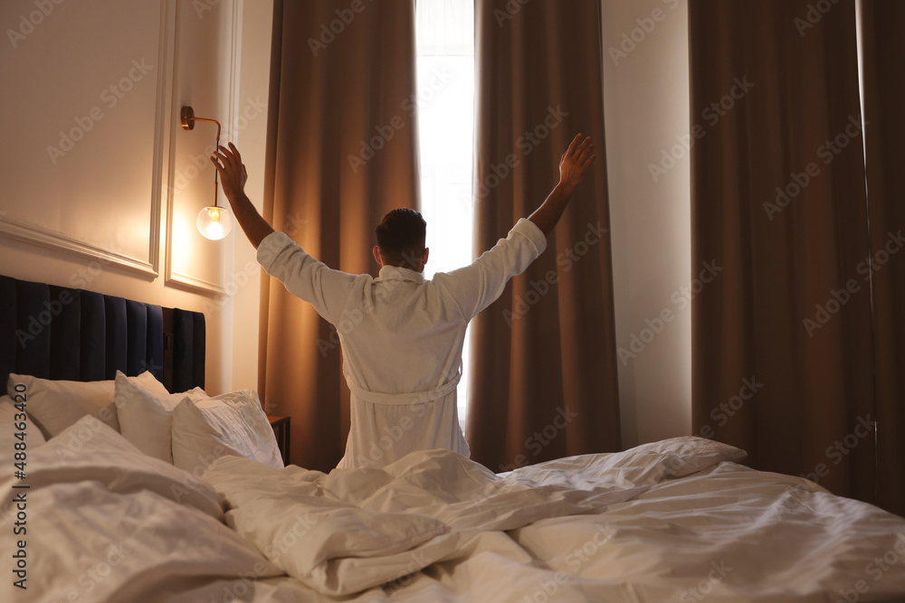 Fototapeta premium Man waking up in hotel room, back view