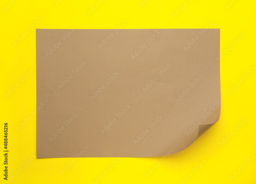 Sheet of brown paper on yellow background, top view Sheet of brown paper on yellow background, top view