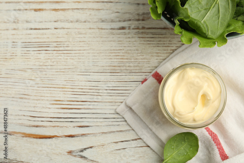 Jar of delicious mayonnaise and fresh spinach on white wooden table, flat lay. Space for text