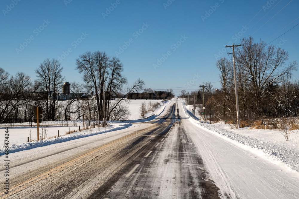 A straight road in the country, freshly plowed and salted after a snow fall.