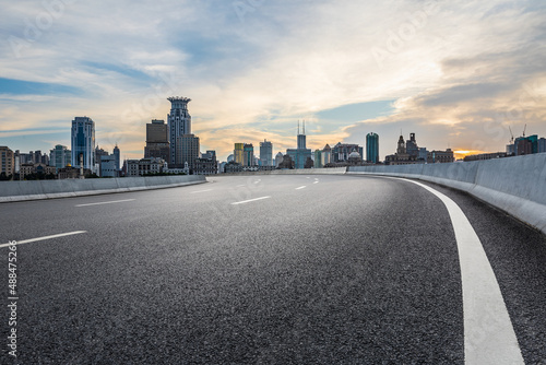 Empty asphalt road and city skyline with modern commercial buildings in Shanghai at sunset, China.