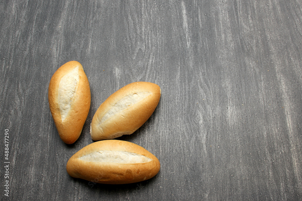 Fototapeta premium Fresh, delicious, hot and freshly made Mexican, French, bolilllo, white bread, loaf on a gray wooden table. Inexpensive food made with wheat flour 