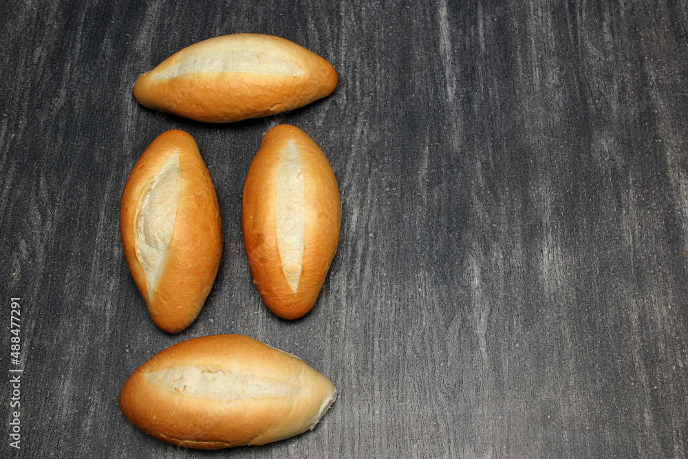 Obraz premium Fresh, delicious, hot and freshly made Mexican, French, bolilllo, white bread, loaf on a gray wooden table. Inexpensive food made with wheat flour 