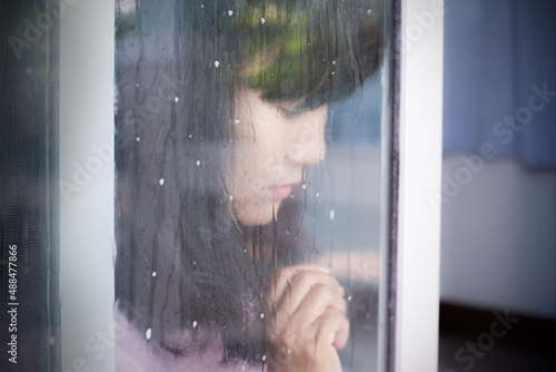 Broken heart concept. Drop water on glass door with blur alone woman sad and cry closc up. for card or poster couple problem, love valentine day, disappointment. authentic black hair asian Thailand.