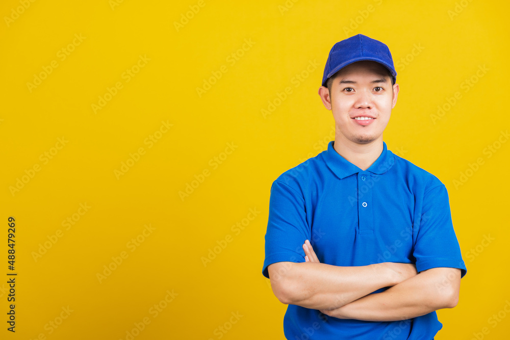 Portrait professional attractive delivery happy man standing he smile wearing blue t-shirt and cap uniform crossed arms looking to camera, studio shot isolated on yellow background Portrait professional attractive delivery happy man standing he smile wearing blue t-shirt and cap uniform crossed arms looking to camera, studio shot isolated on yellow background