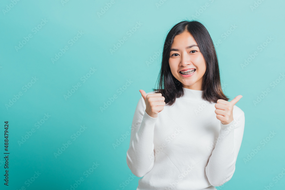 Young beautiful Asian woman cheerful smiling showing finger thumb up, Portrait happy female using showing like the gesture for good sign, studio shot isolated on a blue background Young beautiful Asian woman cheerful smiling showing finger thumb up, Portrait happy female using showing like the gesture for good sign, studio shot isolated on a blue background
