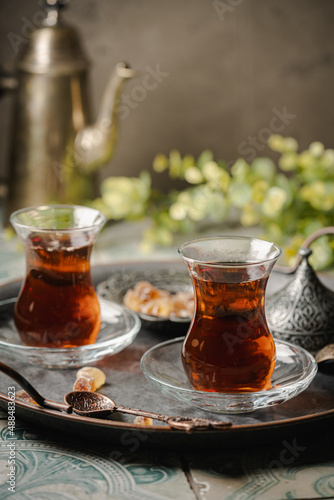 Turkish tea in traditional glass on tray closeup, tile background