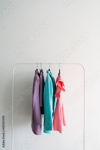 Capsule of pastel color clothes on a rail. closeup