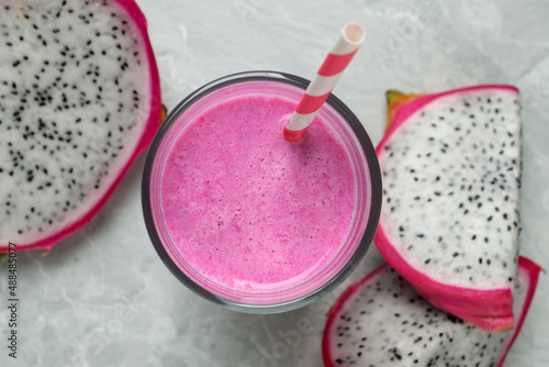 Glass of tasty pitahaya smoothie and fresh dragon fruits on light grey table, flat lay