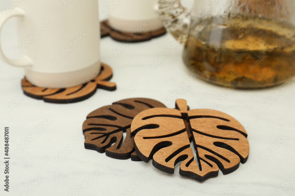 Leaf shaped wooden cup coasters on white table Leaf shaped wooden cup coasters on white table