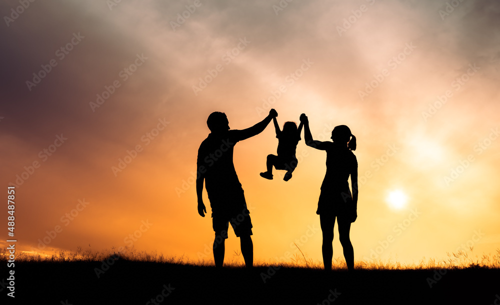 silhouette of parents playing with child at sunset