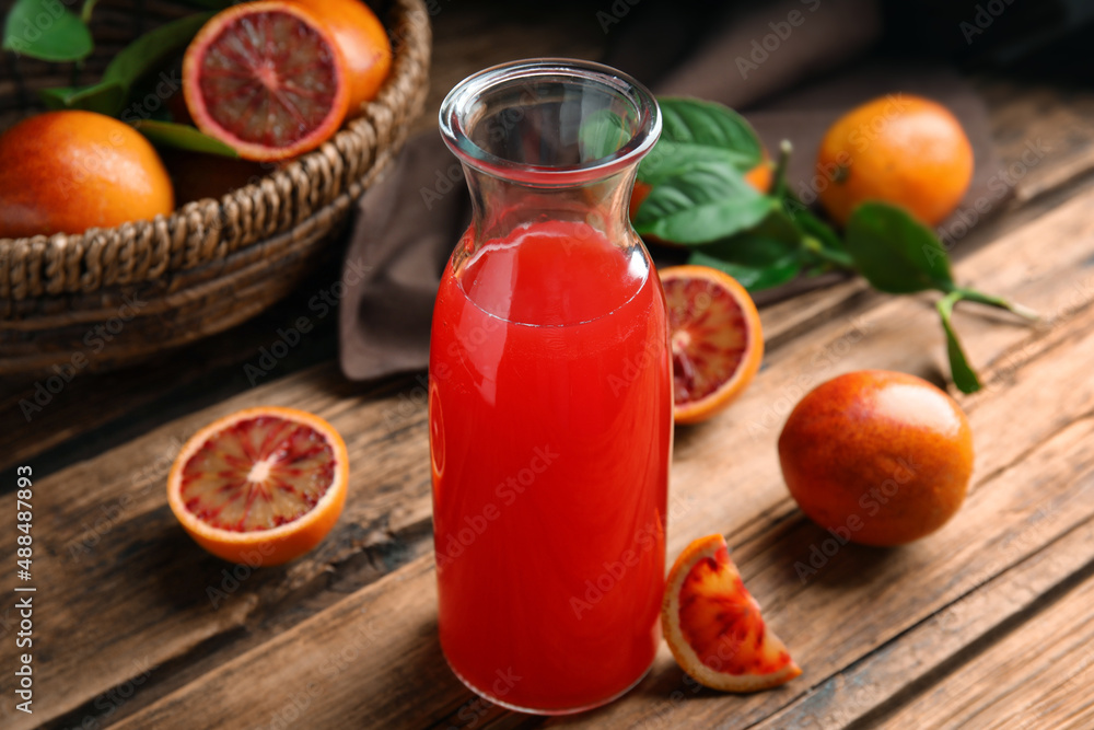 Tasty sicilian orange juice in glass bottle and fruits on wooden table Tasty sicilian orange juice in glass bottle and fruits on wooden table