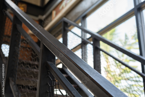 Close-up at metal handrail handle s part of stairway to the the second floor. Building and interior object photo. Partial focus at railing part.