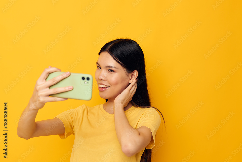 woman with a smartphone in hands fun emotions close-up yellow background unaltered woman with a smartphone in hands fun emotions close-up yellow background unaltered