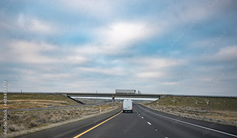 Fototapeta premium Commercial cargo mini van and big rig semi truck with semi trailer running at different directions for delivery loaded cargo