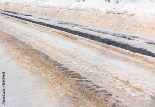 Winter road covered with snow and sprinkled with sand. Snow clearing and road maintenance by municipal services in Russia