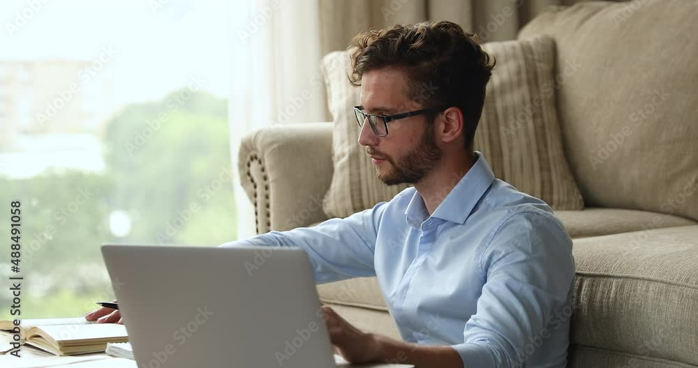 Thoughtful young male student engaged in learning from home analyze information using special literature and laptop. Busy millennial guy prepare scientific research read paper sources online materials Thoughtful young male student engaged in learning from home analyze information using special literature and laptop. Busy millennial guy prepare scientific research read paper sources online materials