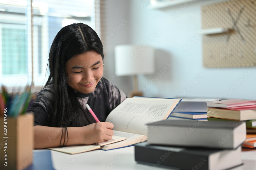 Smiling teenage girl doing homework at home. Smiling teenage girl doing homework at home.