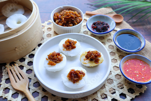 Steamed rice cake top with preserved turnip served with sweet soy sauce and chili sauce - In Chinese food called Chwee Kueh on wood table