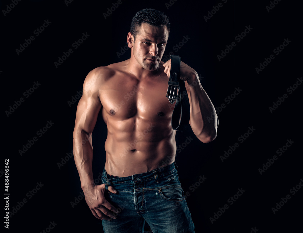 Handsome muscular man posing. Guy in jeans with perfect abdominal muscles.