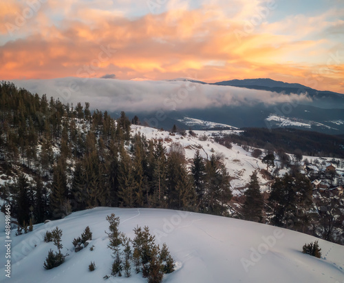 Beautiful landscape with creeping fogs on the snowy mountain slopes of the Rhodopes, Bulgaria at sunrise