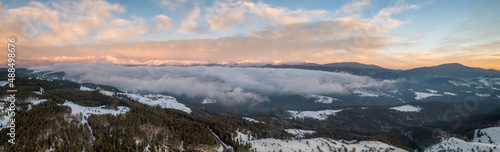 Beautiful landscape with creeping fogs on the snowy mountain slopes of the Rhodopes, Bulgaria at sunrise
