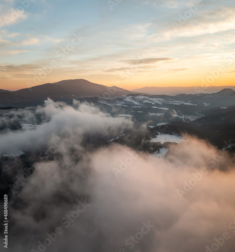 Beautiful landscape with creeping fogs on the snowy mountain slopes of the Rhodopes, Bulgaria at sunrise