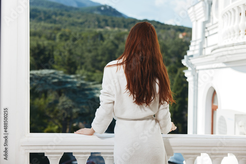 pretty woman in a white robe on the balcony bit on green nature Relaxation concept