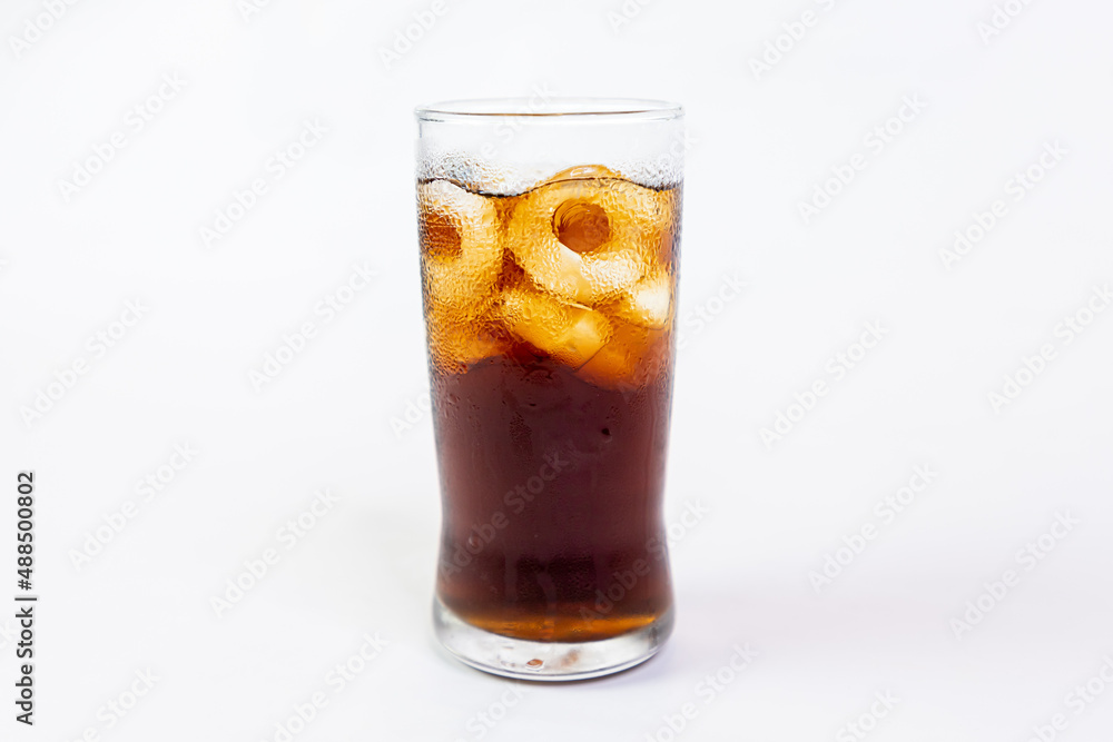 Coca-Cola flavored black soft drink with ice in a clear glass on a white background. Coca-Cola flavored black soft drink with ice in a clear glass on a white background.