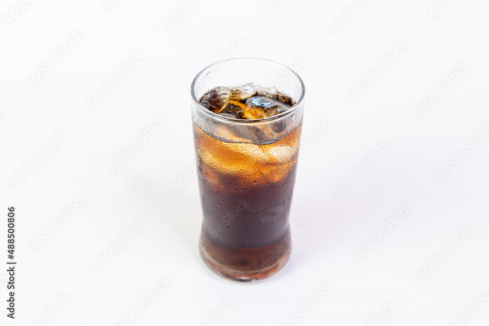 Coca-Cola flavored black soft drink with ice in a clear glass on a white background. Coca-Cola flavored black soft drink with ice in a clear glass on a white background.