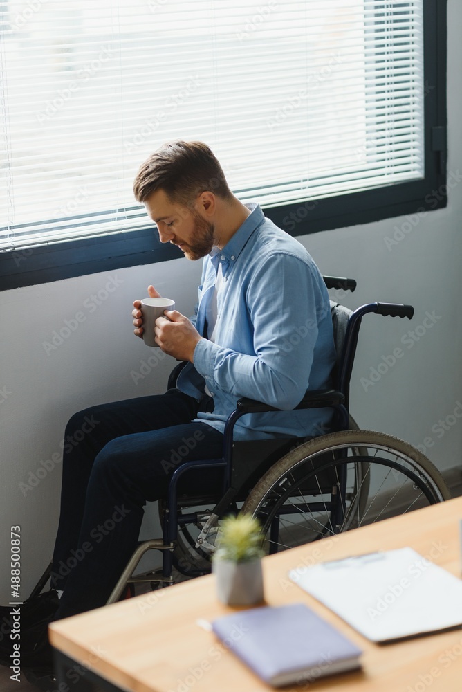 Sad disabled person feeling lonely at home or clinic. Depression on self isolation. Upset man in wheelchair looks out of large window and dreams, in living room interior Sad disabled person feeling lonely at home or clinic. Depression on self isolation. Upset man in wheelchair looks out of large window and dreams, in living room interior