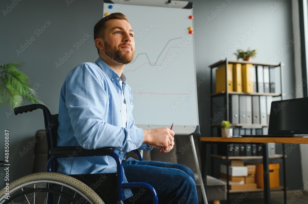 Handicapped Businessman Sitting On Wheelchair And Using Computer In Office