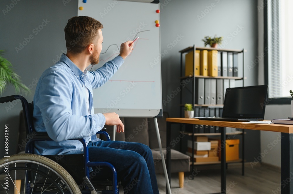 Handicapped Businessman Sitting On Wheelchair And Using Computer In Office Handicapped Businessman Sitting On Wheelchair And Using Computer In Office