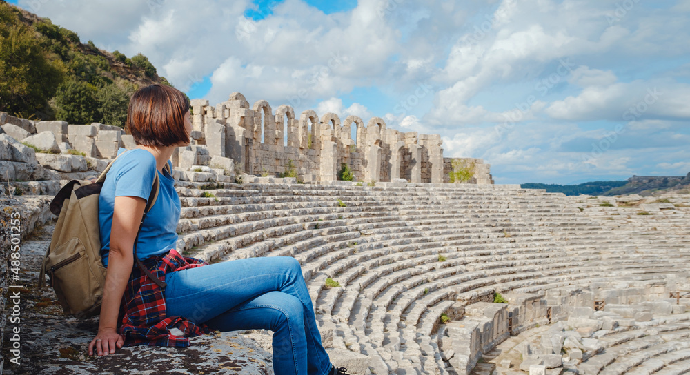 walk in Antalya Turkey on warm October afternoon. Pretty tourist woman with backpack at ruins of ancient city of Perge