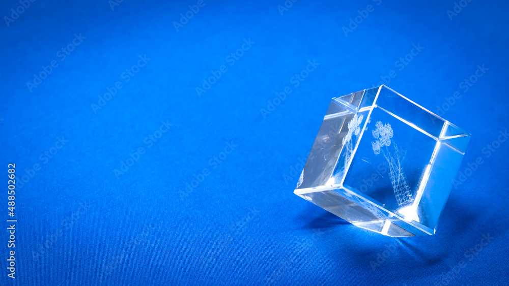 Jewelry work. A glass cube on a blue background with a flower painted inside Jewelry work. A glass cube on a blue background with a flower painted inside