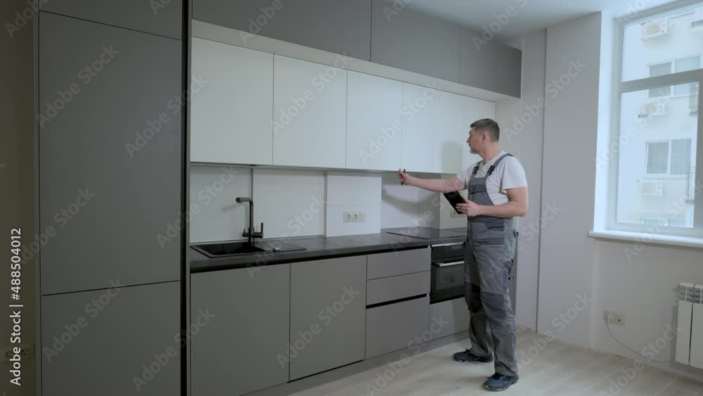The builder checks the quality of the installation of kitchen furniture construction The builder checks the quality of the installation of kitchen furniture construction
