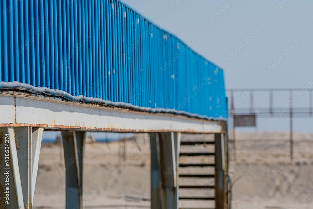Perspective view of blue metal walkway with blurred background.
