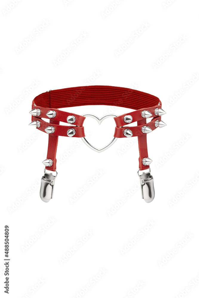 Detailed shot of a red garter made as two leather bands with garter clips, steel spikes and a heart-shaped ring. The fancy suspender is isolated on the white background. Detailed shot of a red garter made as two leather bands with garter clips, steel spikes and a heart-shaped ring. The fancy suspender is isolated on the white background.