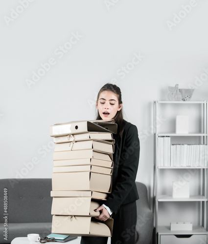 Stressed young businesswoman with folders of documents. Job, occupation and overworking concept. Successful female manager, beautiful secretary girl. © Volodymyr