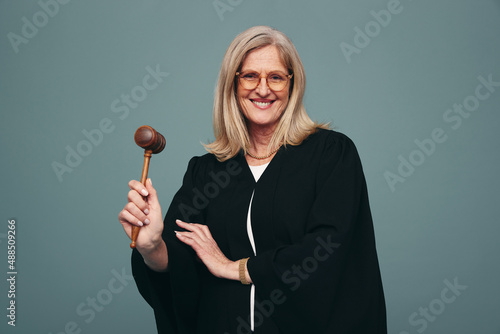 Cheerful mature judge holding up a gavel in a studio photo