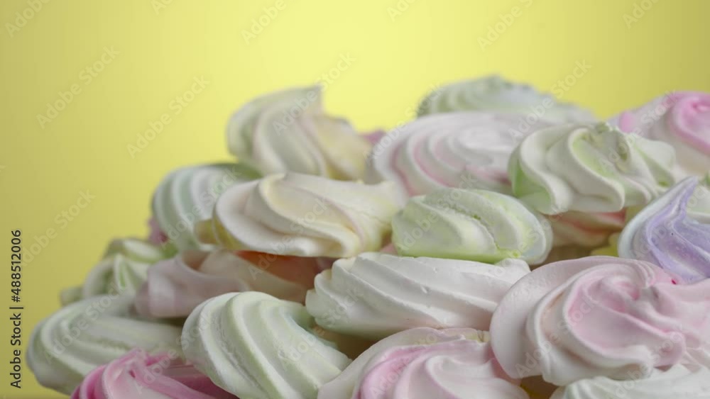 Swirls of sweet meringue rotating on yellow background. Sweet meringue yellow, pink and purple color in confectionery. Close up shot of protein and sugar cookies. Slow motion ready, 4K at 59.94fps. Swirls of sweet meringue rotating on yellow background. Sweet meringue yellow, pink and purple color in confectionery. Close up shot of protein and sugar cookies. Slow motion ready, 4K at 59.94fps.