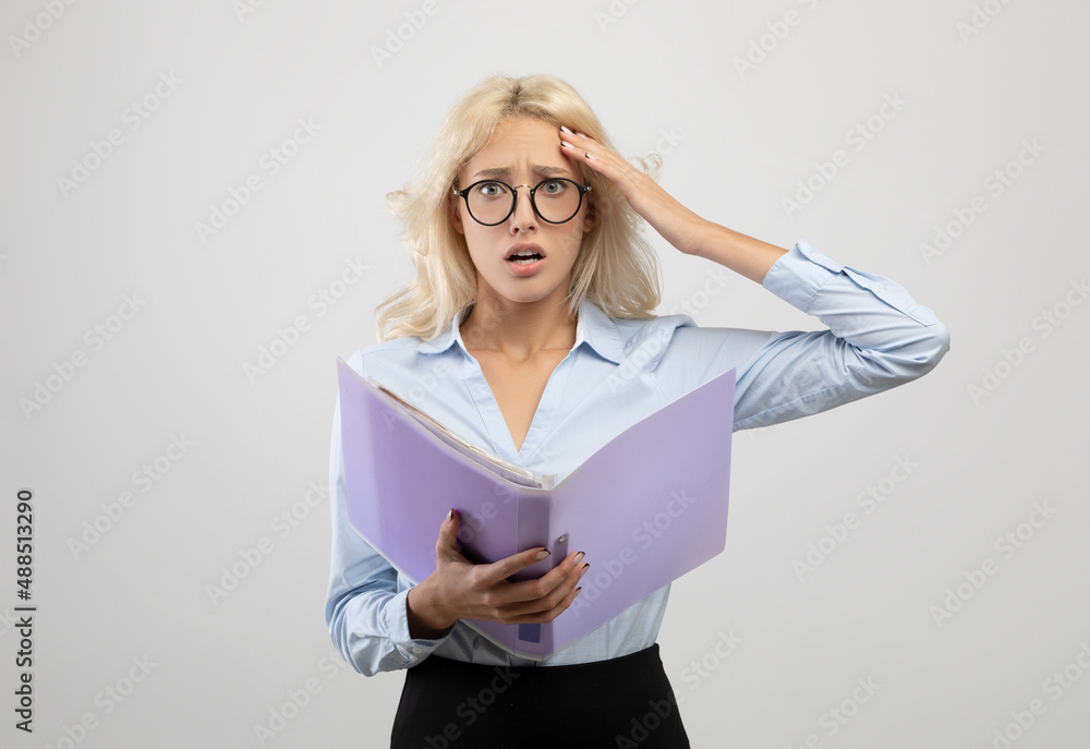 Stressed young office employee with documents, shocked over mistake, missing deadline, posing on light grey background Stressed young office employee with documents, shocked over mistake, missing deadline, posing on light grey background