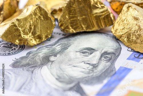 Precious metals and currency investment concept : Gold colored iron ore on a US dollar money, depicting investing in gold market to diversify risk through the use of futures contract and derivatives.