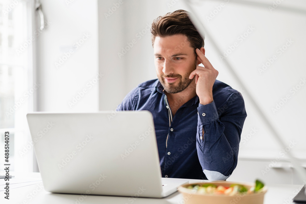 Concentrated businessman working on laptop at desk in office Concentrated businessman working on laptop at desk in office