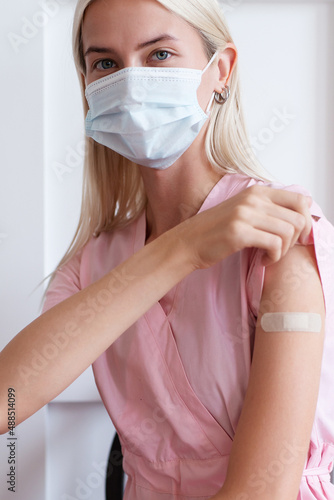 Woman showing her arm with bandage after receiving vaccination.